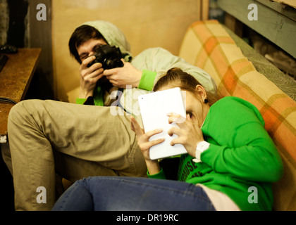 Caucasian man photographing petite amie sur canapé Banque D'Images