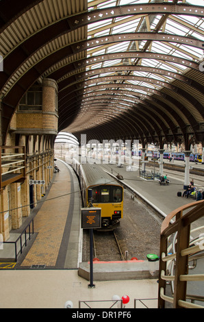 Vue intérieure d'trainshed avec fer et verre, toit trains fixes et les gens qui attendent sur platfom - La gare de York, North Yorkshire, Angleterre, Royaume-Uni. Banque D'Images