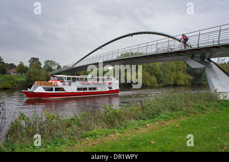Passagers bénéficient de la voile voyage sur la rivière Ouse à bord d'un petit bateau de croisière, en passant sous le pont du millénaire en tant que cycliste traverse overhead - York, England, UK. Banque D'Images