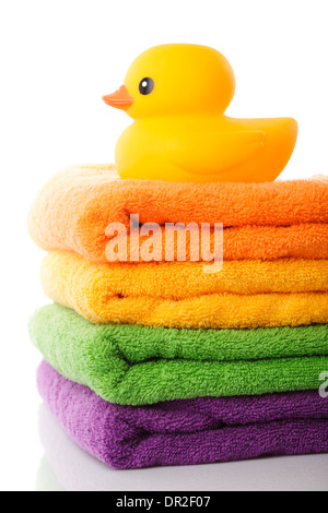 Pile de serviettes colorées et canard en caoutchouc jaune isolated on white Banque D'Images