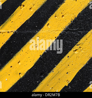 Rayé jaune et noir attention sur mur de béton Banque D'Images