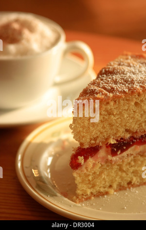 Café et gâteau cappuccino avec une tranche de confiture et de crème gâteau rempli Banque D'Images