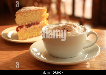 Café et gâteau cappuccino avec une tranche de confiture et de crème gâteau rempli Banque D'Images