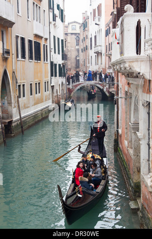 Gondolier sur canal passe sous un pont et de photographier les participants du carnaval de Venise les participants costumés Banque D'Images