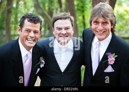Ministre posant avec un beau couple de mariage gay qu'il vient de marier. *L'accent est mis sur le ministre. Banque D'Images