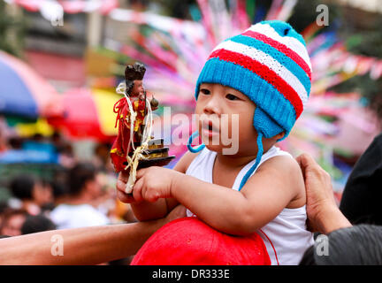 La région métropolitaine de Manille, Philippines - 18 janvier, 2014 : un baby holding de droit de l'Enfant Jésus tandis que porté par son père pendant la "Lakbayaw" Festival du Tagalog mots, 'Lakbay" (voyage) et "ayaw" (danse) dans la zone urbaine de Tondo, Manille, qui unit presque toutes les organisations, les écoles, les groupes communautaires et les gens de Tondo dans le cadre de leur dévotion à Santo Nino.Les Philippines sont le seul pays catholique en Asie du sud-est autour de 93 pour cent avec l'exercice de la foi. Credit : Herman Lumanog/Alamy Live News Banque D'Images