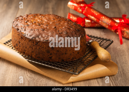 Gâteau aux fruits de Noël prêt à glace sur grille de refroidissement avec des craquelins à l'arrière-plan Banque D'Images