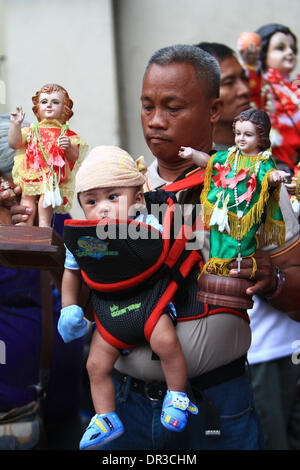 Manille, Philippines. 19 Jan, 2014. Un homme est titulaire d'une statue de la Santo Nino tout en portant son fils pendant la fête de la Santo Nino à Manille, Philippines, le 19 janvier 2014. Les Philippines tenue week-end célébrations pour marquer le jour de fête de Santo Nino, le respect que les dévots croient est la statue miraculeuse du saint Enfant Jésus. Credit : Rouelle Umali/Xinhua/Alamy Live News Banque D'Images