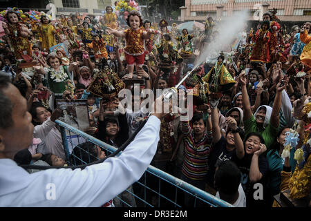 Manille, Philippines. 19 Jan, 2014. Les catholiques philippins élever leur Santo Nino statues qu'ils sont pulvérisés avec de l'eau bénite pendant la fête de Santo Nino dans une église dans le quartier pauvre de Tondo à Manille, Philippines, le 19 janvier 2014. Le festival est célébré chaque troisième dimanche de janvier, qui rend hommage à l'Enfant Jésus plus communément connue sous le nom de ''Santo Nino'' pour les catholiques philippins.Photo : Ezra Acayan/NurPhoto Acayan Crédit : Ezra/NurPhoto ZUMAPRESS.com/Alamy/Live News Banque D'Images