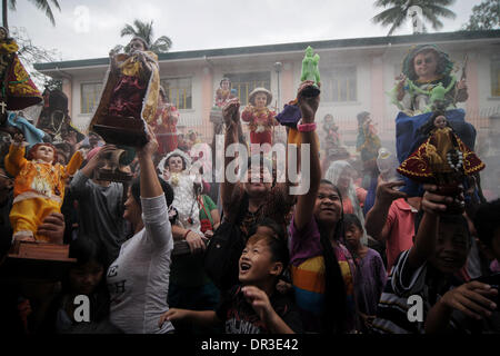 Manille, Philippines. 19 Jan, 2014. Les catholiques philippins élever leur Santo Nino statues qu'ils sont pulvérisés avec de l'eau bénite pendant la fête de Santo Nino dans une église dans le quartier pauvre de Tondo à Manille, Philippines, le 19 janvier 2014. Le festival est célébré chaque troisième dimanche de janvier, qui rend hommage à l'Enfant Jésus plus communément connue sous le nom de ''Santo Nino'' pour les catholiques philippins.Photo : Ezra Acayan/NurPhoto Acayan Crédit : Ezra/NurPhoto ZUMAPRESS.com/Alamy/Live News Banque D'Images