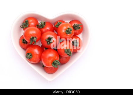 Tomates cerise sur la plaque en forme de cœur Banque D'Images