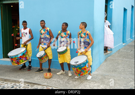 Quatre jeunes hommes se tenant debout sur la rue tambour contre un mur bleu dans le Pelourinho, Salvador de Bahia, Brésil Banque D'Images