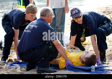 Techniciens d'exécution une victime sur une planche dorsale après avoir été blessé sur une plage Banque D'Images