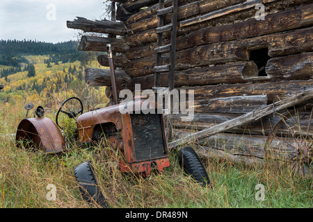 Ancienne grange du tracteur par un journal, sur une ferme près de probable, région de Cariboo-Chilcotin, Colombie-Britannique Banque D'Images
