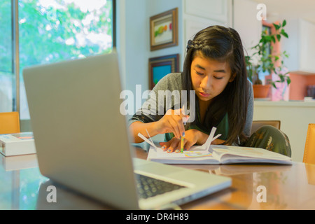 Chinese girl doing homework at table Banque D'Images