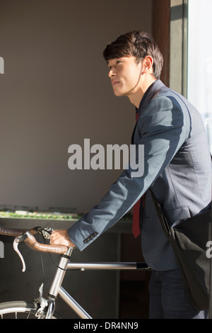 Korean businessman wheeling bicycle in office Banque D'Images