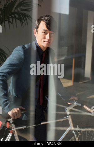 Korean businessman wheeling bicycle in office Banque D'Images