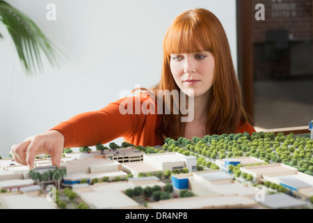 Caucasian businesswoman examining scale model Banque D'Images