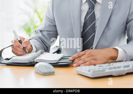 Mid section of a businessman writing in diary Banque D'Images