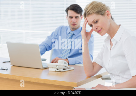 Contrarié businesswoman with man working on laptop Banque D'Images