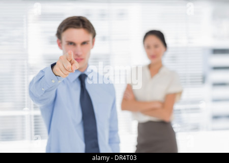 Businessman pointing towards camera with woman in office Banque D'Images