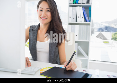 Smiling casual femme photo editor à l'aide de tablette graphique Banque D'Images