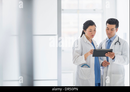 Doctors using digital tablet in hospital corridor Banque D'Images