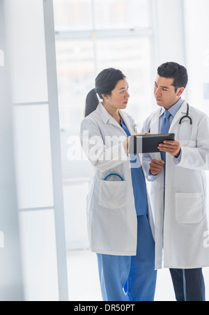 Doctors using digital tablet in hospital corridor Banque D'Images