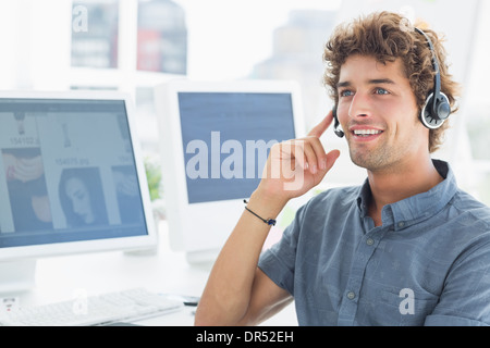 Smiling casual young man with headset in office Banque D'Images