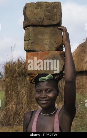 Jeune femme porte des blocs de boue sur la tête. Banque D'Images