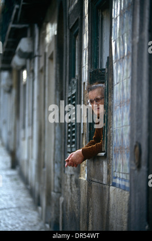 Une vieille dame regarde le monde passer de sa porte dans la rue du quartier de Bica Lisbonne la capitale portugaise. Banque D'Images