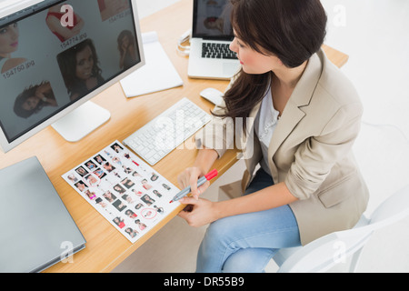 Artiste féminin assis à un bureau avec ordinateurs de bureau Banque D'Images