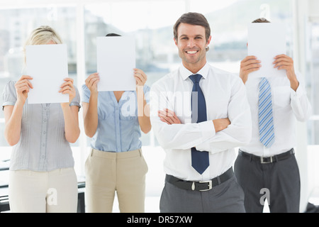 Businessman holding avec des collègues du papier vierge en face de visages Banque D'Images