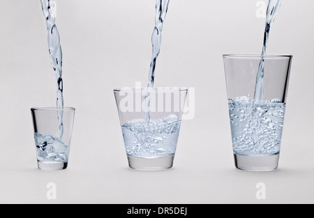 Verser de l'eau dans des verres sur fond gris clair Banque D'Images