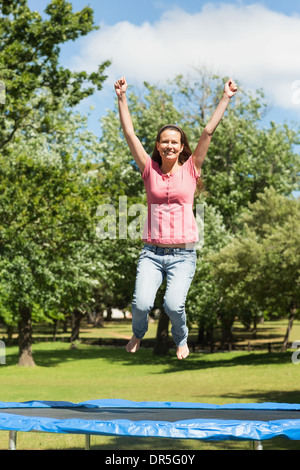 Happy woman jumping high sur trampoline dans park Banque D'Images