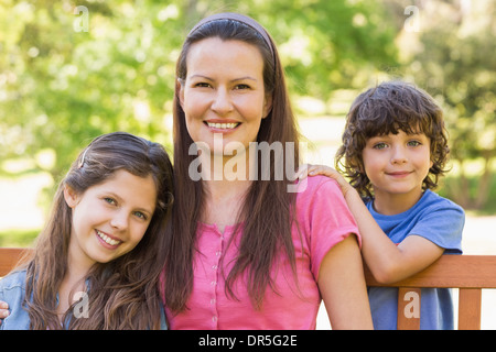 Femme souriante avec des enfants assis sur le banc de parc Banque D'Images