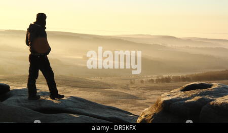 Hathersage Moor, Derbyshire, Royaume-Uni. 20e Janvier 2014. Une colline walker enquêtes la scène de Misty Higger Tor sur un gel-elg Hathersage Moor dans le Peak District National Park le soleil dore le paysage golden sur 'Blue Monday' soi-disant la journée la plus déprimante de l'année. Un retour à l'humidité et de vent à travers le Royaume-Uni est prévue pour plus tard cette semaine. Credit : Deborah Vernon/Alamy Live News Banque D'Images