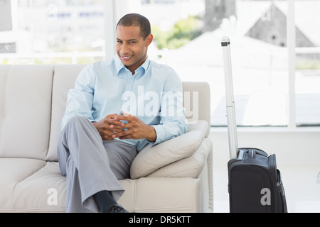 Happy businessman sitting on sofa en attendant de partir en voyage d'affaires Banque D'Images