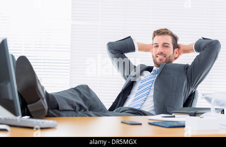 Ambiance confident businessman sitting avec jambes sur 24 Banque D'Images