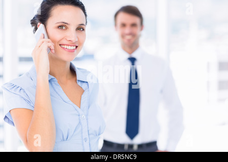 Femme sur appel avec collègue masculin en arrière-plan Banque D'Images
