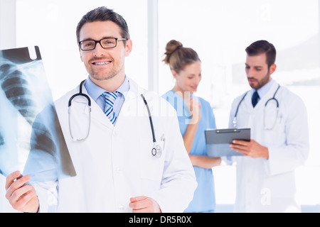 Male doctor examining x-ray avec des collègues derrière Banque D'Images