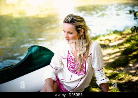 Jeune femme assise au bord de la rivière, contreforts des Alpes, Bavière, Allemagne Banque D'Images