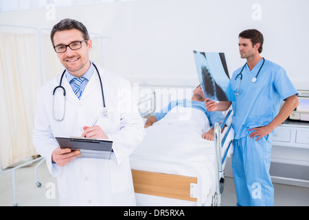 Doctors holding reports by patient at hospital Banque D'Images