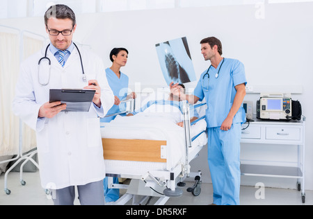 Doctors holding reports by patient at hospital Banque D'Images