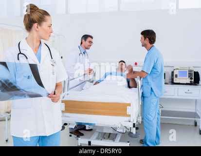 Doctor holding x-ray avec des collègues et des patients à l'hôpital Banque D'Images