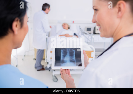 Doctors examining x-ray with patient flou en arrière-plan Banque D'Images