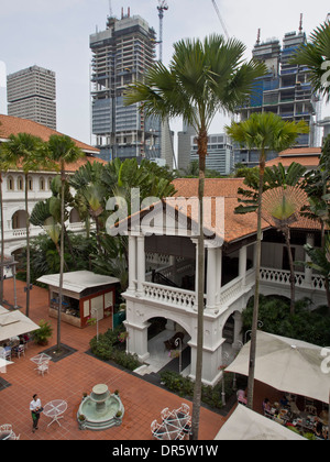 La cour de la célèbre Raffles Hotel de style colonial avec des gratte-ciel de la ville moderne en arrière-plan.Singapour Banque D'Images