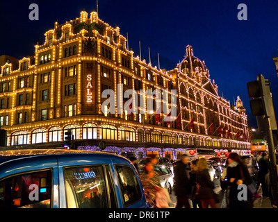 Vente Harrods department store au crépuscule avec Sale sign occupé avec les consommateurs et passant taxis & Vintage Harrods Bus dans b/g Knightsbridge Londres SW1 Banque D'Images