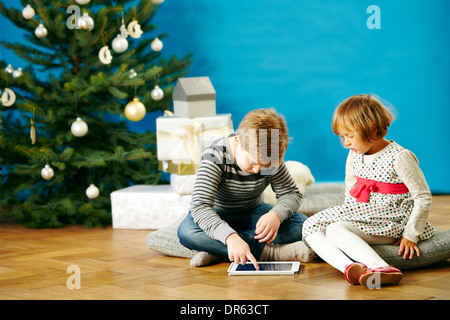 Enfants jouant avec tablette numérique la veille de Noël, Munich, Bavière, Allemagne Banque D'Images