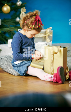 Little girl unwrapping Christmas presents, Munich, Bavière, Allemagne Banque D'Images